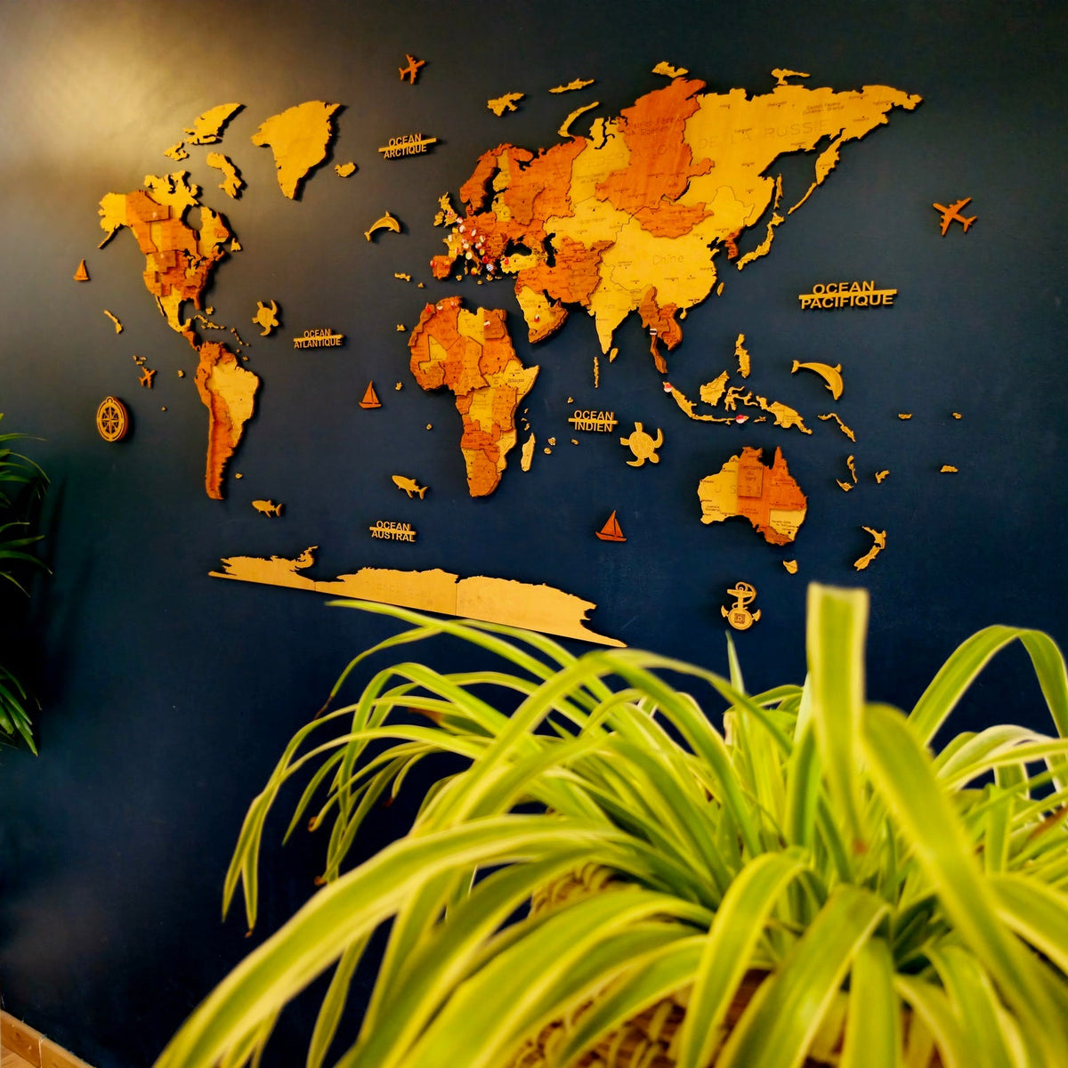 Carte du monde murale en bois installée au-dessus d’un canapé